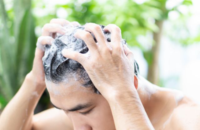 下をむいて髪の毛をシャンプーで洗う男性