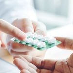 薬を渡している医師と受け取っている男性の手
