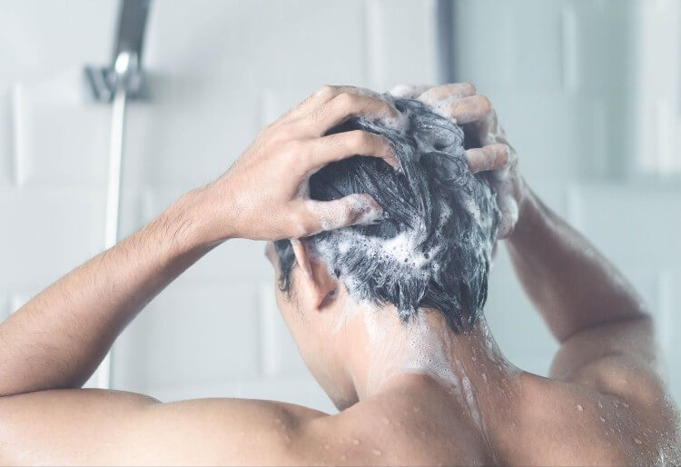 シャワーで髪を洗う男性